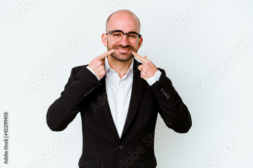 Young business caucasian bald man isolated on blue background smiles, pointing fingers at mouth.