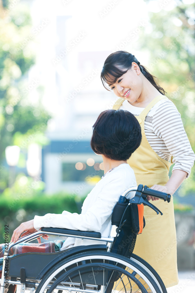 Obraz premium 車椅子に乗ったシニア女性と話す女性介護士