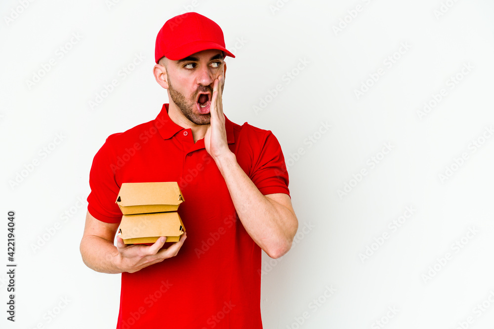 Young caucasian delivery man isolated on white background is saying a secret hot braking news and looking aside Young caucasian delivery man isolated on white background is saying a secret hot braking news and looking aside