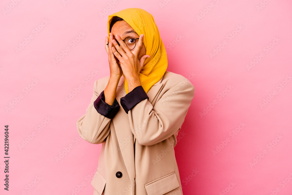 Young business muslim woman isolated on pink background blink through fingers frightened and nervous. Young business muslim woman isolated on pink background blink through fingers frightened and nervous.