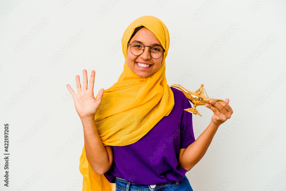 Young muslim woman holding a lamp isolated on white background smiling cheerful showing number five with fingers. Young muslim woman holding a lamp isolated on white background smiling cheerful showing number five with fingers.