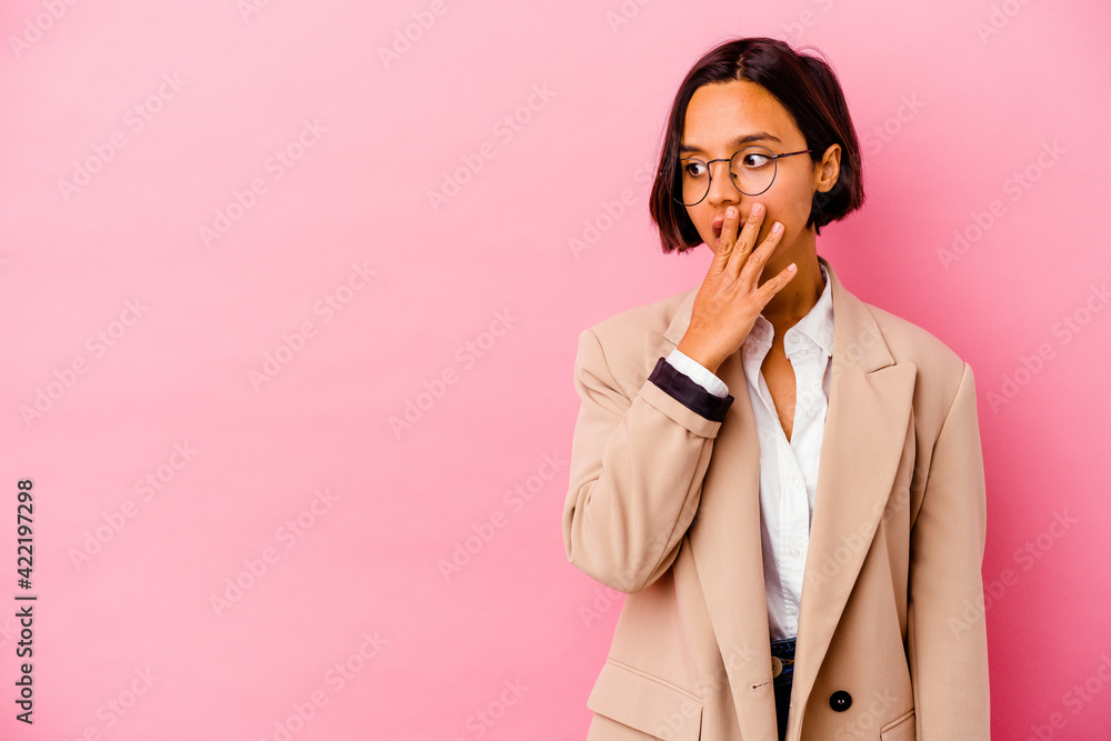 Young business mixed race woman isolated on pink background thoughtful looking to a copy space covering mouth with hand. Young business mixed race woman isolated on pink background thoughtful looking to a copy space covering mouth with hand.
