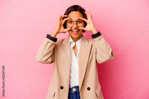 Young business mixed race woman isolated on pink background keeping eyes opened to find a success opportunity. © Asier
