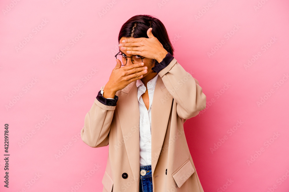 Young business mixed race woman isolated on pink background blink at the camera through fingers, embarrassed covering face. Young business mixed race woman isolated on pink background blink at the camera through fingers, embarrassed covering face.