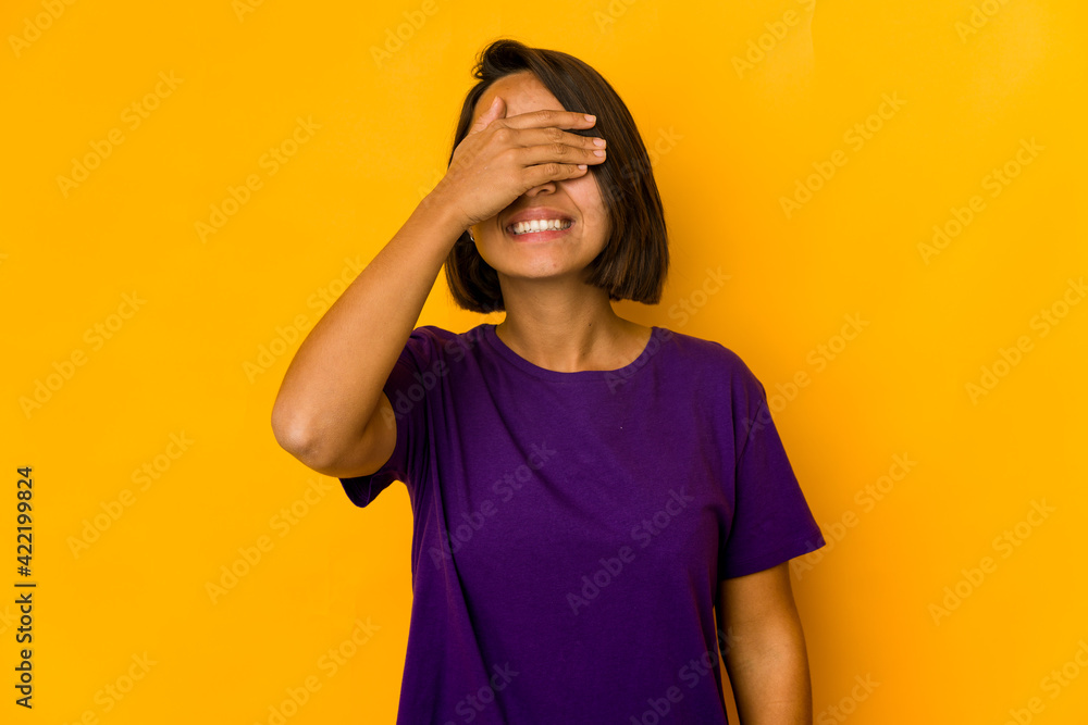 Young hispanic woman isolated on yellow covers eyes with hands, smiles broadly waiting for a surprise. Young hispanic woman isolated on yellow covers eyes with hands, smiles broadly waiting for a surprise.