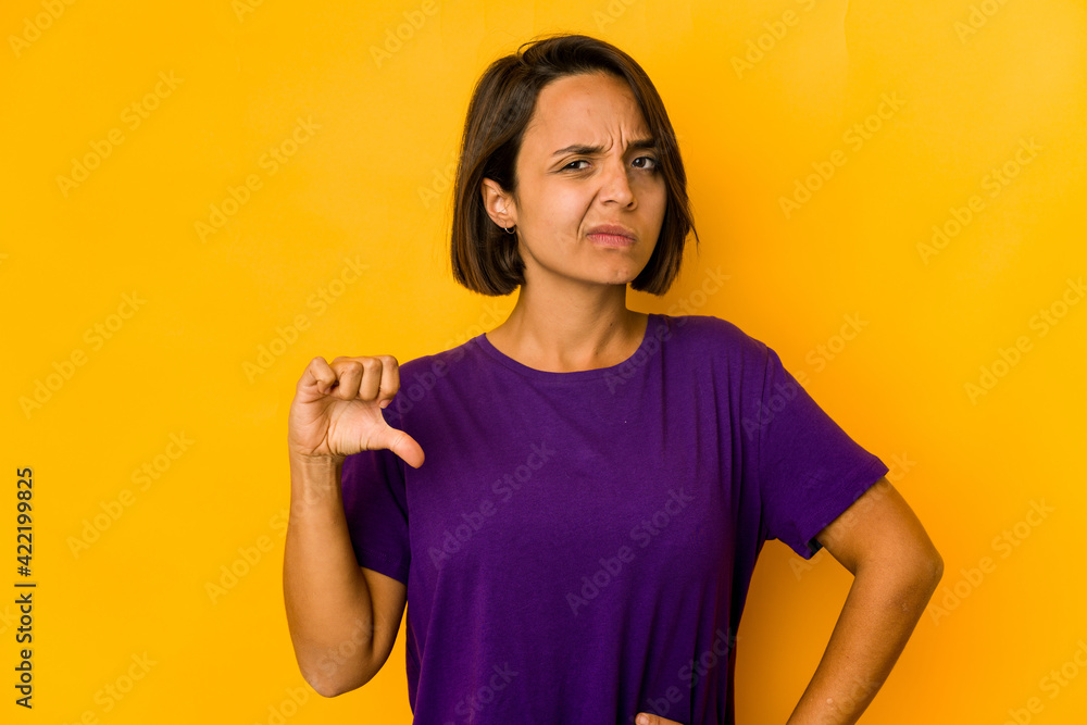 Young hispanic woman isolated on yellow showing thumb down, disappointment concept. Young hispanic woman isolated on yellow showing thumb down, disappointment concept.