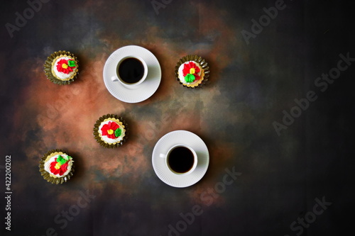 Pair of cups of fresh black strong coffee and sweet cream cake in basket on big dark background. Top view, flat lay
