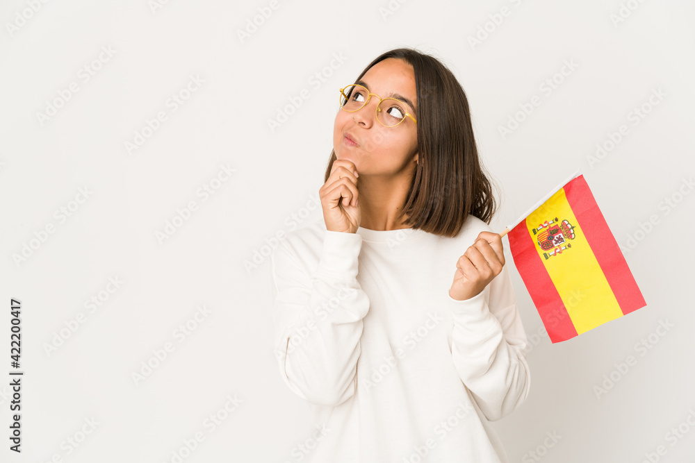Young hispanic mixed race woman holding a spanish flag looking sideways with doubtful and skeptical expression. Young hispanic mixed race woman holding a spanish flag looking sideways with doubtful and skeptical expression.