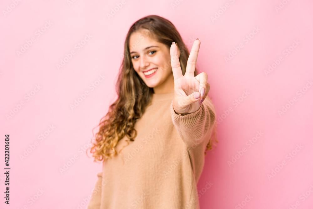 Young caucasian woman joyful and carefree showing a peace symbol with fingers. Young caucasian woman joyful and carefree showing a peace symbol with fingers.