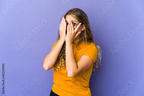 Young caucasian cute woman blink through fingers frightened and nervous.
