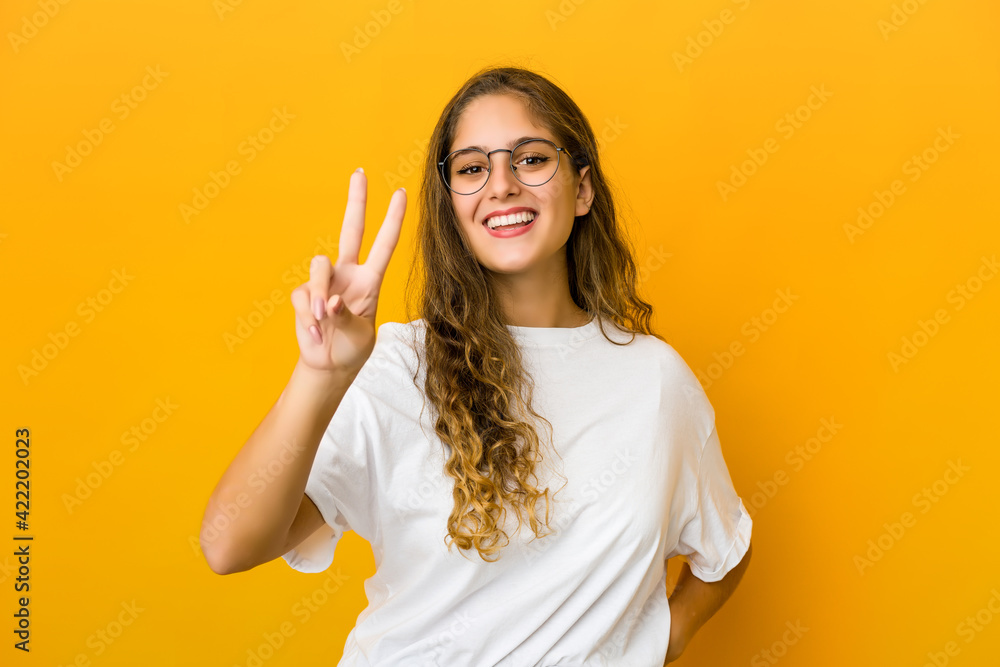 Young caucasian woman showing victory sign and smiling broadly. Young caucasian woman showing victory sign and smiling broadly.