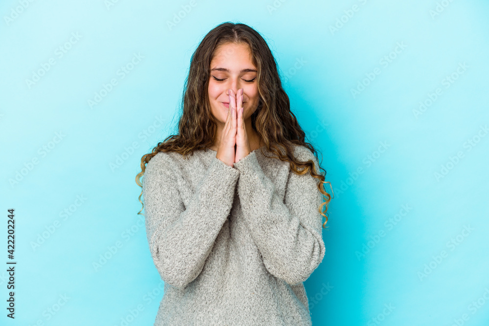 Young caucasian curly hair woman isolated holding hands in pray near mouth, feels confident. Young caucasian curly hair woman isolated holding hands in pray near mouth, feels confident.