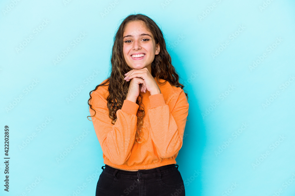 Young caucasian curly hair woman isolated keeps hands under chin, is looking happily aside. Young caucasian curly hair woman isolated keeps hands under chin, is looking happily aside.