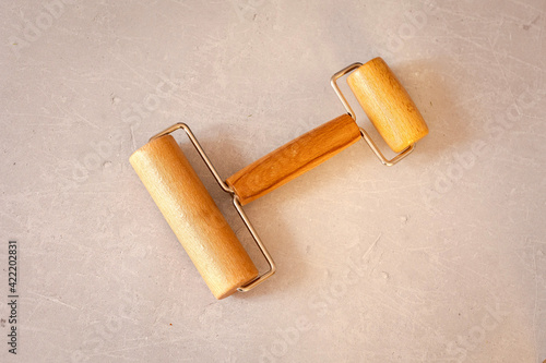 Wooden double-sided roller for rolling out dough or clay on marble table. Professional working tool. Flat lay, top view