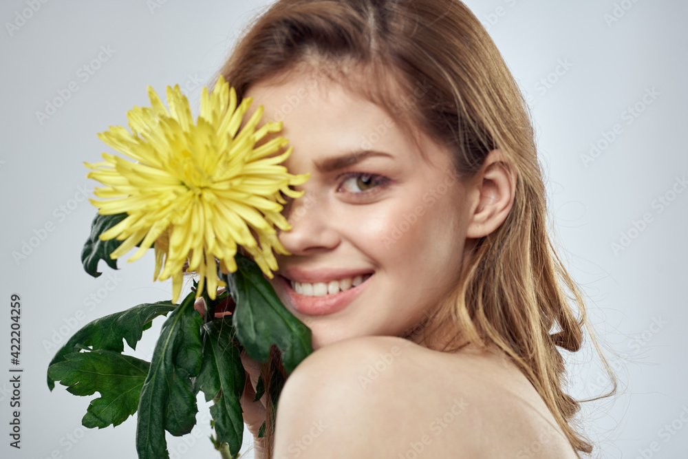 Portrait of a beautiful woman with a yellow flower on a light background cropped with Copy Space Model Portrait of a beautiful woman with a yellow flower on a light background cropped with Copy Space Model