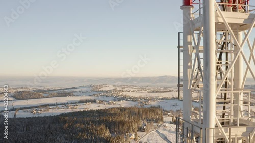 Aerial rising beside tall communication tower, telephone connection pole