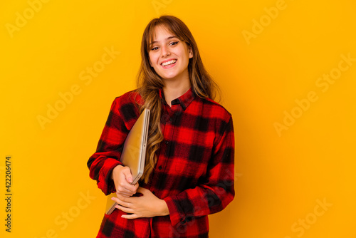 Young caucasian woman holding a laptop isolated happy, smiling and cheerful. © Asier