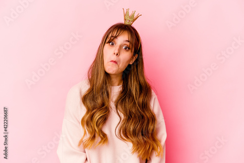 Young caucasian woman with princess crown isolated shrugs shoulders and open eyes confused.