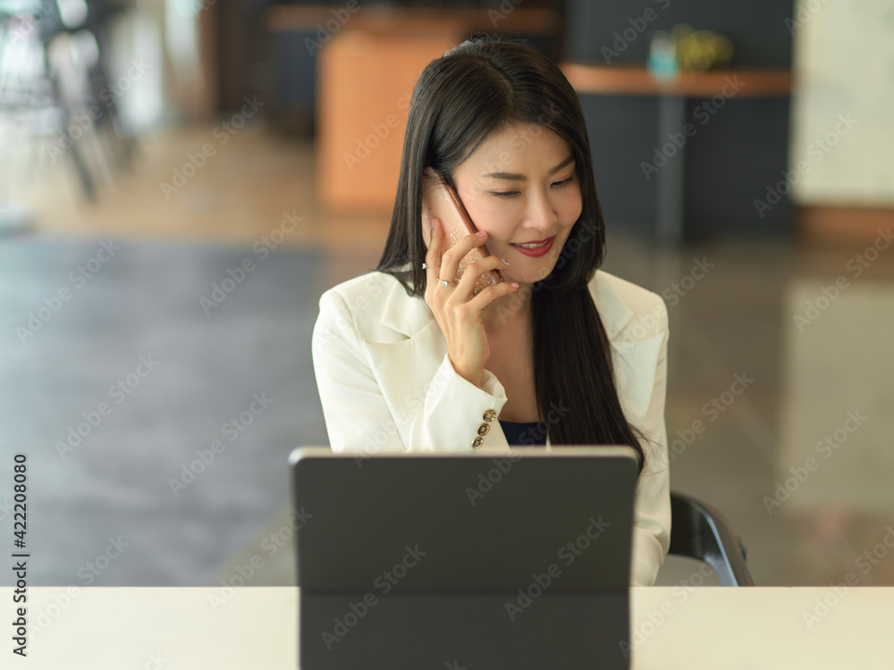 Portrait of businesswoman smiling and talking on the phone while sitting at workplace Portrait of businesswoman smiling and talking on the phone while sitting at workplace