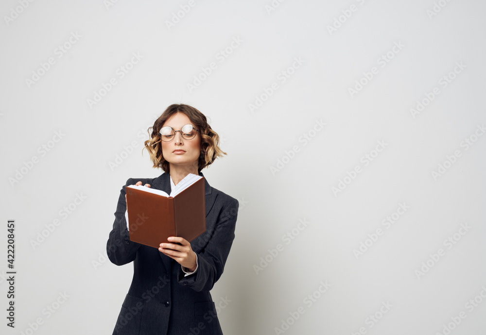 A woman in a suit with a notebook in her hands on a light background work model A woman in a suit with a notebook in her hands on a light background work model