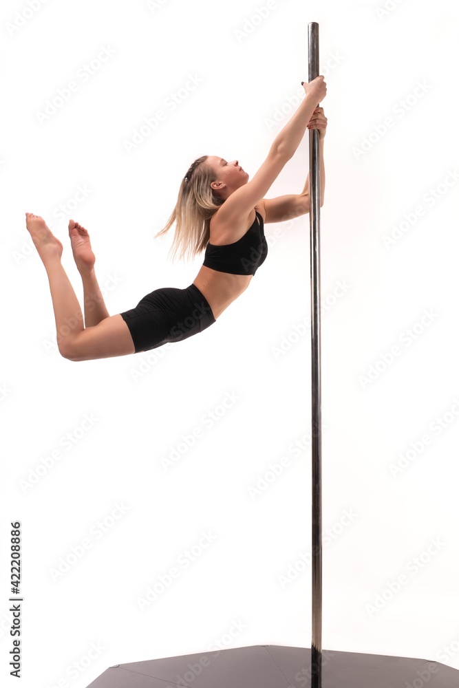 Slim girl performing acrobatic exercise on pole