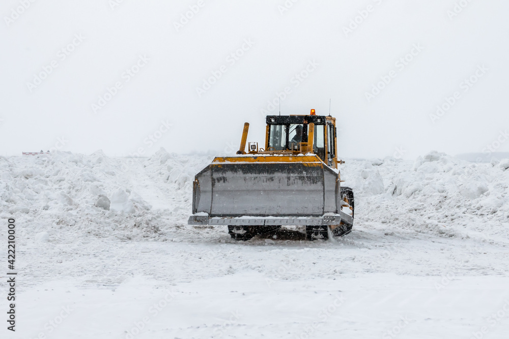 Yellow bulldozer removes snowdrifts in a severe snowstorm at winter Yellow bulldozer removes snowdrifts in a severe snowstorm at winter