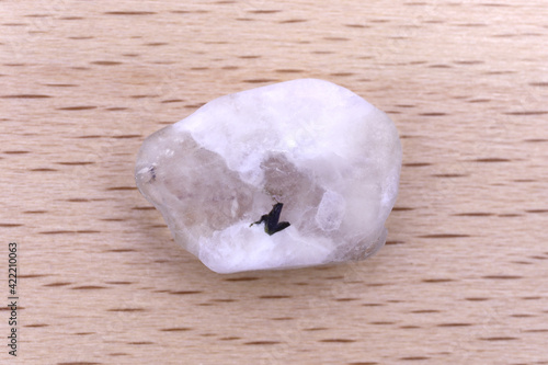 Foto Moon stone jewel texture on light wood background. Macro closeup.