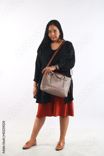 Young woman in casual outfit with stylish bag on white background.