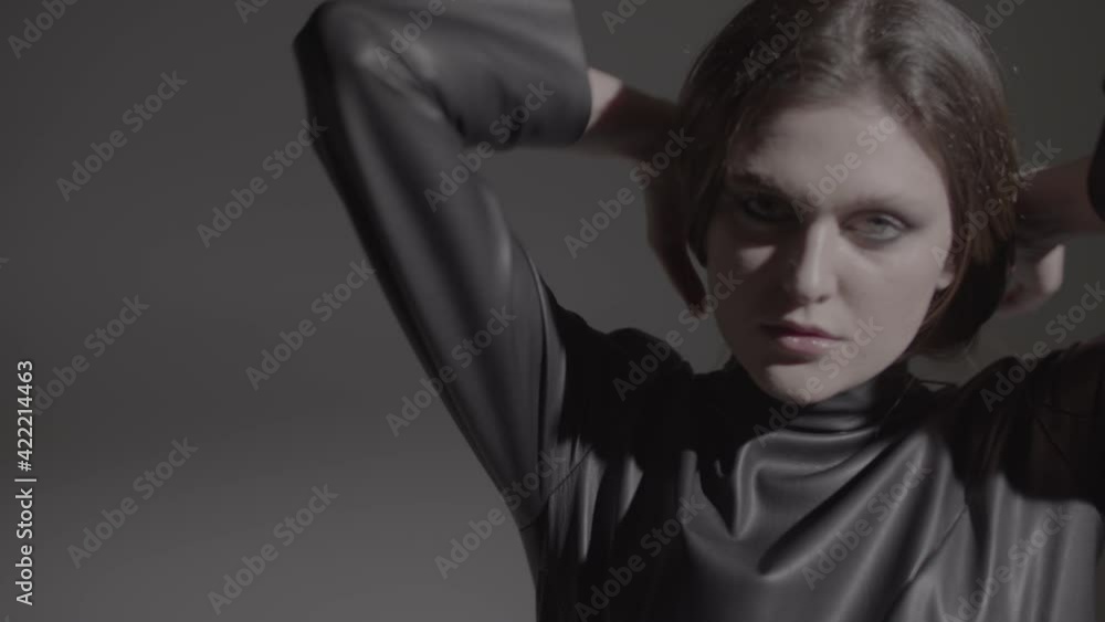 Dark hair woman posing in the black dress in the studio lights. Young attractive woman wearing a black dress. Ungraded video. Dark hair woman posing in the black dress in the studio lights. Young attractive woman wearing a black dress. Ungraded video.