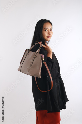 Young woman in casual outfit with stylish bag on white background.