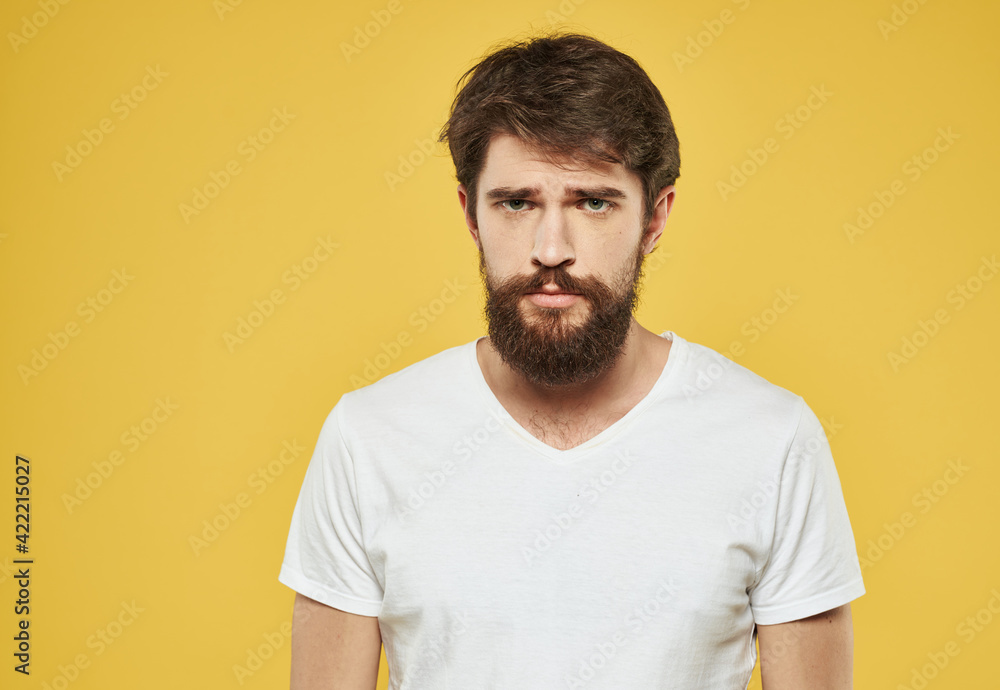 Portrait of a sad man on a yellow background cropped view of a white t-shirt Portrait of a sad man on a yellow background cropped view of a white t-shirt