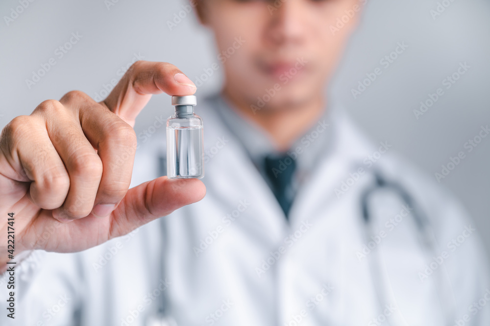 Doctor or scientist carries a syringe and a vaccine against COVID-19, vaccination and laboratory experiments. Concept of protection against the COVID-19 virus. Doctor or scientist carries a syringe and a vaccine against COVID-19, vaccination and laboratory experiments. Concept of protection against the COVID-19 virus.