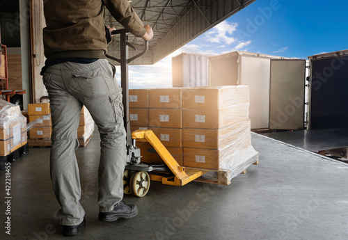 Warehouse Worker Unloading Shipment Boxes into Cargo Container Truck. Cargo Trailer Truck Parked Loading at Dock Warehouse. Delivery Service. Shipping Warehouse Logistics. Freight Truck Transportation