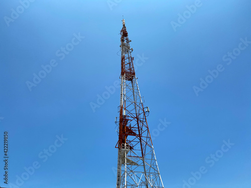View of an old red and white telecommunication tower looking up from ground level