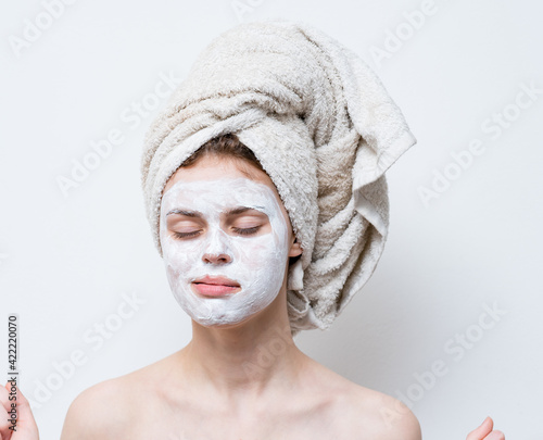 nude woman with white cream on her face and a towel on her head