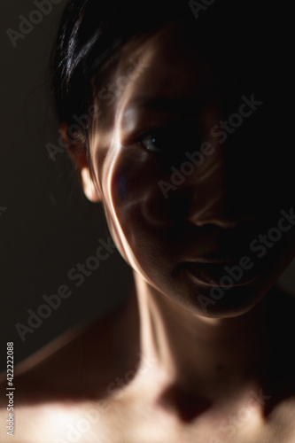 Art portrait. Human spirit. Soul reincarnation. Esoteric harmony. Asian woman silhouette with abstract shadow pattern on face skin isolated on dark night background.