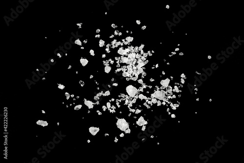 Pieces of white sea salt on a black background. clear crystalline pebbles. white ice cubes