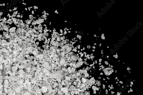 Pieces of white sea salt on a black background. clear crystalline pebbles. white ice cubes