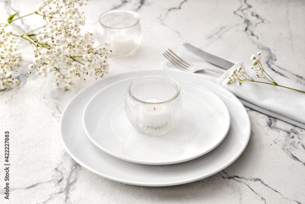 Beautiful table setting with burning candles and floral decor on light background Beautiful table setting with burning candles and floral decor on light background