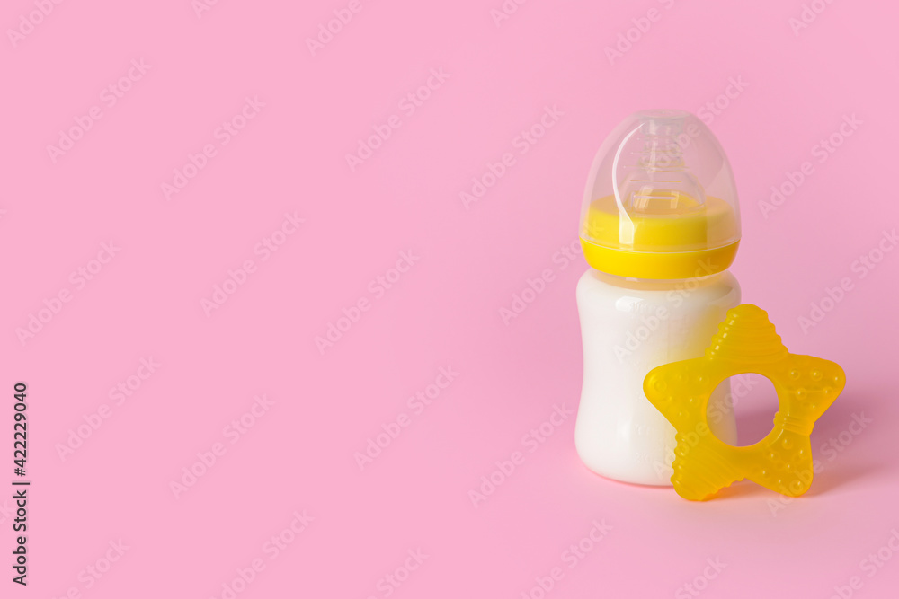 Bottle of milk for baby and teether on color background Bottle of milk for baby and teether on color background