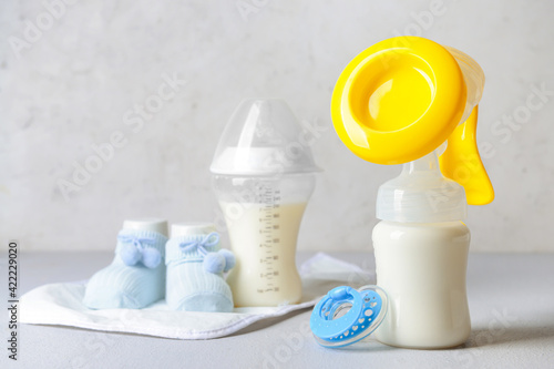 Breast pump and baby accessories on light background