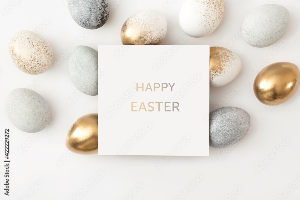 Golden and gray eggs with a paper white card on a white background. Minimal easter concept. - obrazy, fototapety, plakaty 