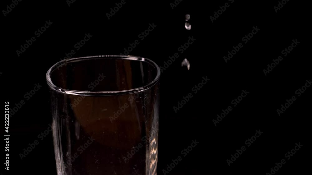 Empty glass with ice cubes on a black background. Ice falling into an empty glass on black background, slow motion. Empty glass with ice cubes on a black background. Ice falling into an empty glass on black background, slow motion.