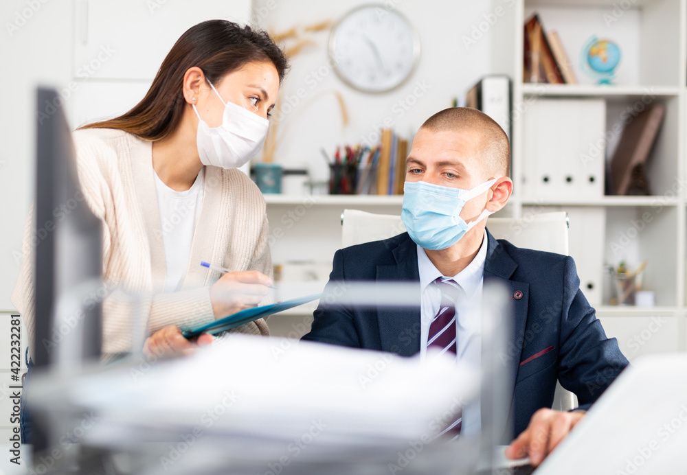 Businessman and businesswoman in protecrive mask working together at office