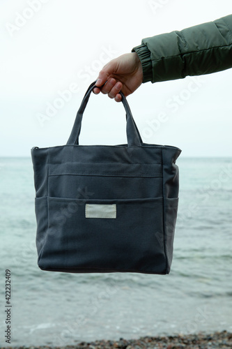 Female hand hold stylish eco bag against sea © Atlas