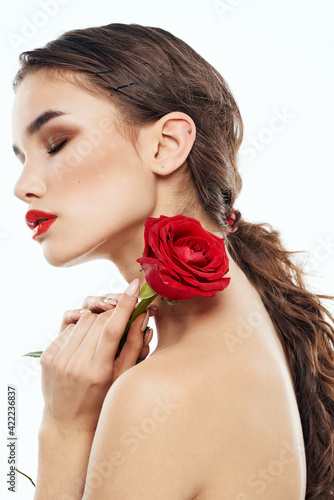 Charming lady with red rose in hands of naked shoulders makeup model