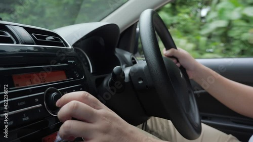 Close up image of driver's hand press button on car audio system, listening music during trip