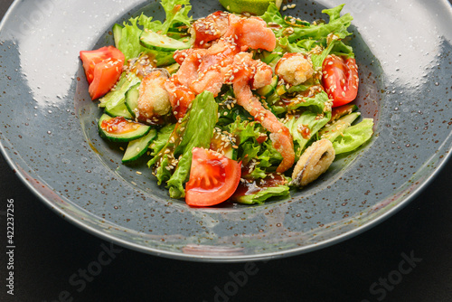 Rare fried salmon steaks in fresh vegetable salad. Delicious dinner, healthy food concept. Over black background.