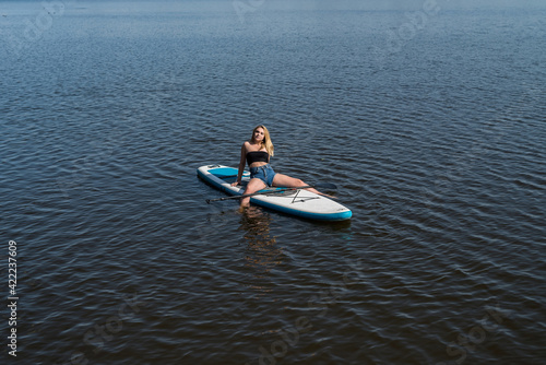 Young female surfer lying on sup board and rest at nature © RomanR