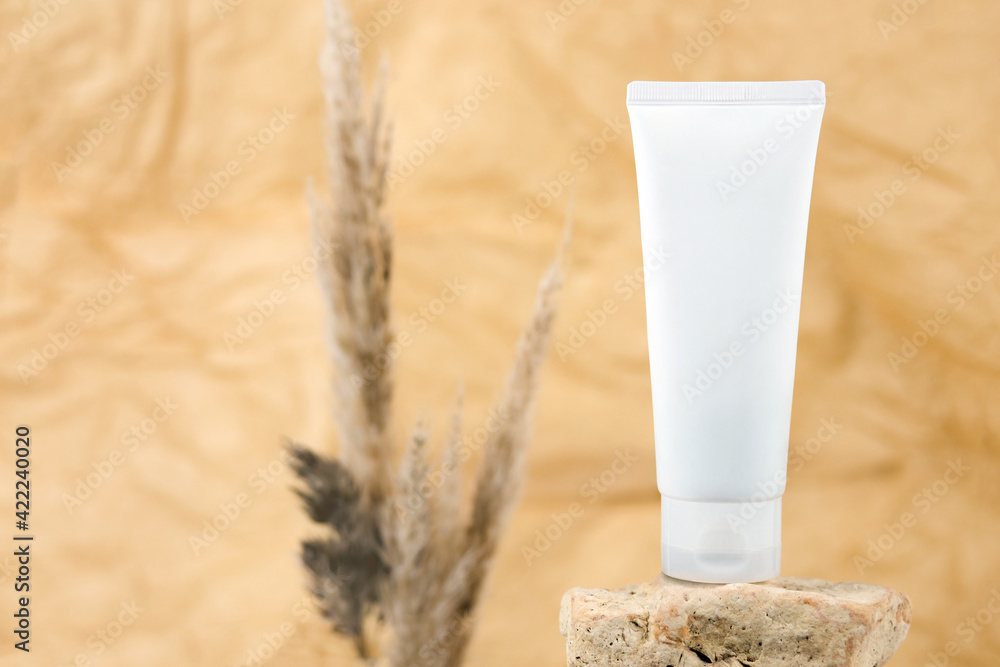 White squeeze bottle plastic tube for branding of medicine or cosmetics - cream, gel, skin care. Cosmetic bottle container on rock on beige brown blurred background, cosmetic packaging mockup. White squeeze bottle plastic tube for branding of medicine or cosmetics - cream, gel, skin care. Cosmetic bottle container on rock on beige brown blurred background, cosmetic packaging mockup.